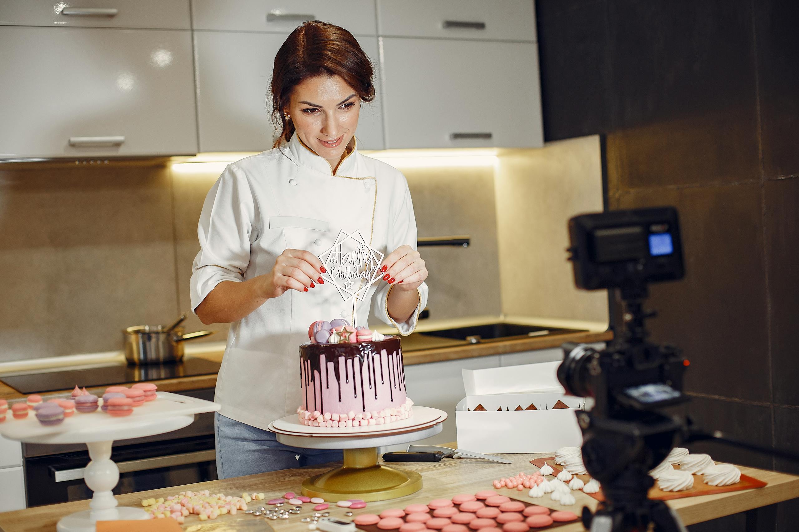 Positive woman presenting cake decoration during pastry class online in contemporary kitchen